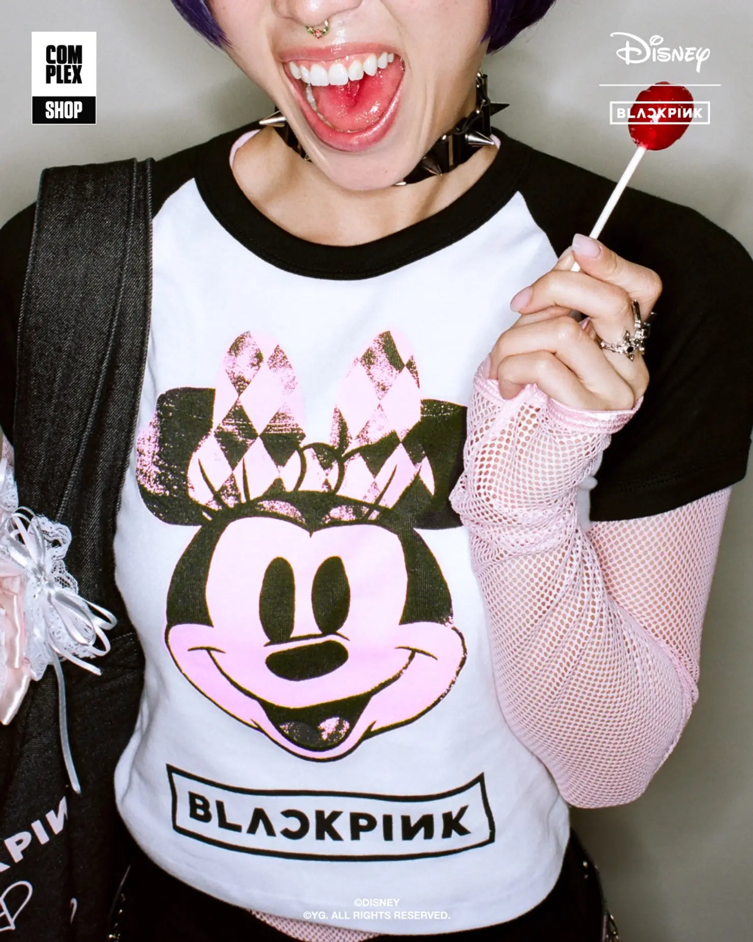 パンクスタイルのミニーマウスデザインが施された白いベースボールTシャツを着用し、キャンディーを持つモデル