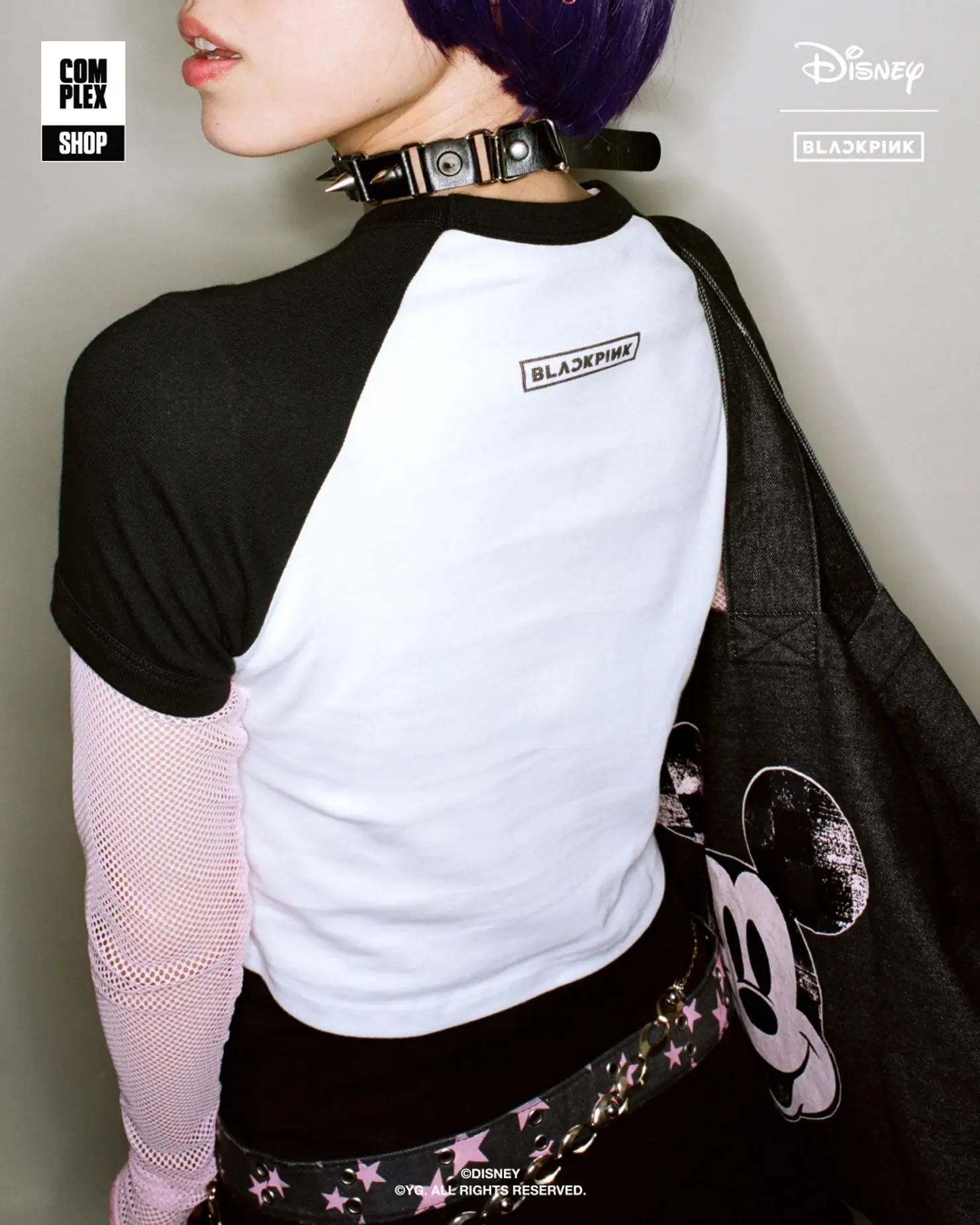 BLACKPINKロゴ入りの白いベースボールTシャツを着用し、パンクアクセサリーでコーディネートしたモデルの後ろ姿