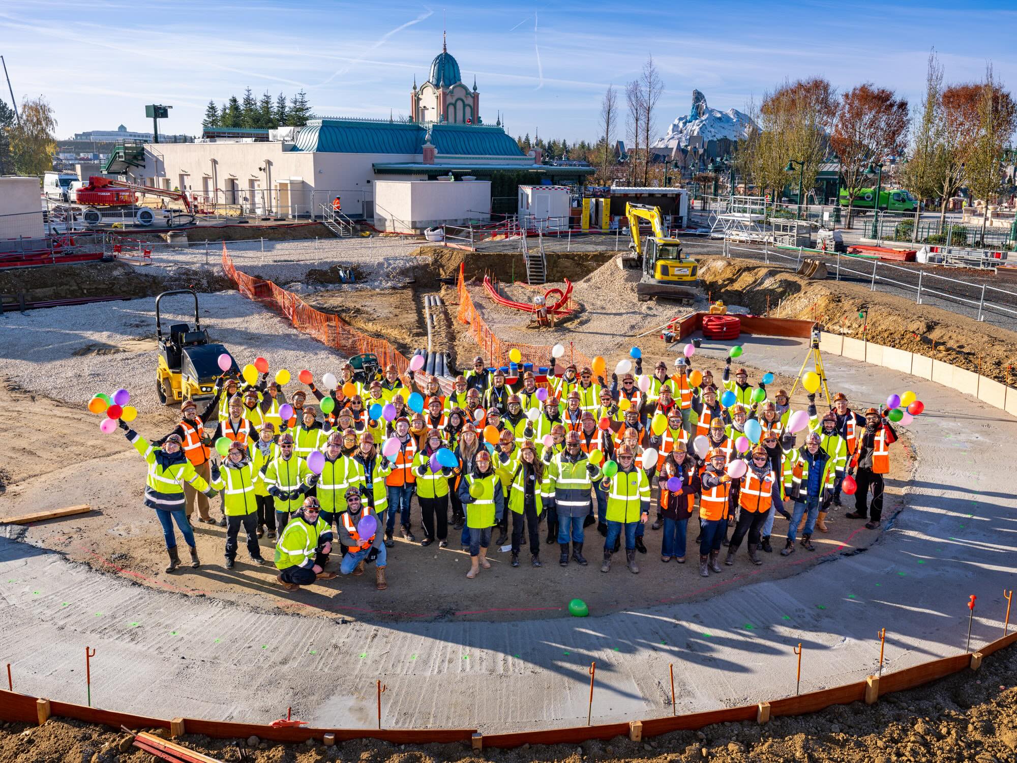 建設現場で風船を持って記念撮影する工事関係者たち