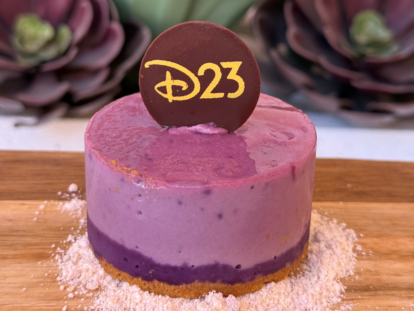 D23ロゴの金文字チョコプレートがのった紫グラデーションのウベ風ミニチーズケーキ