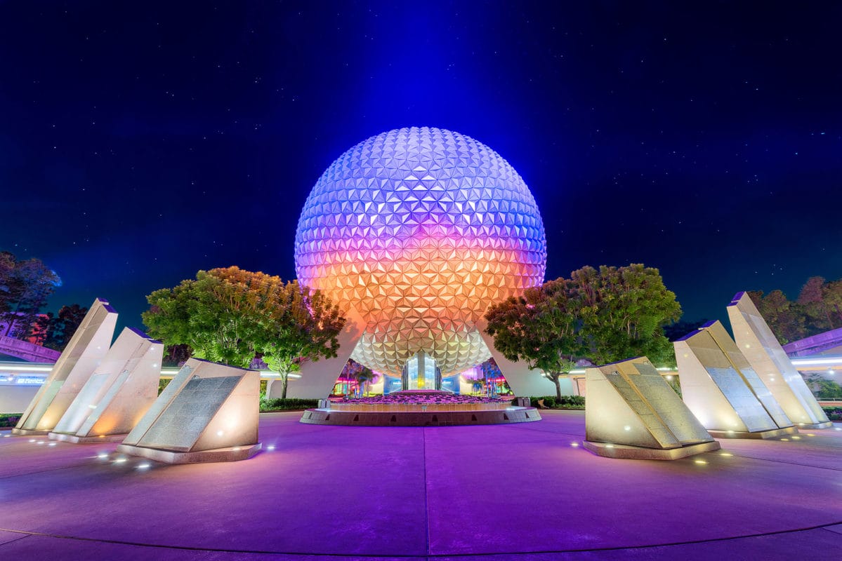 夜のEPCOTでオレンジからパープル、ブルーへのグラデーション照明に輝くスペースシップ・アースの球体