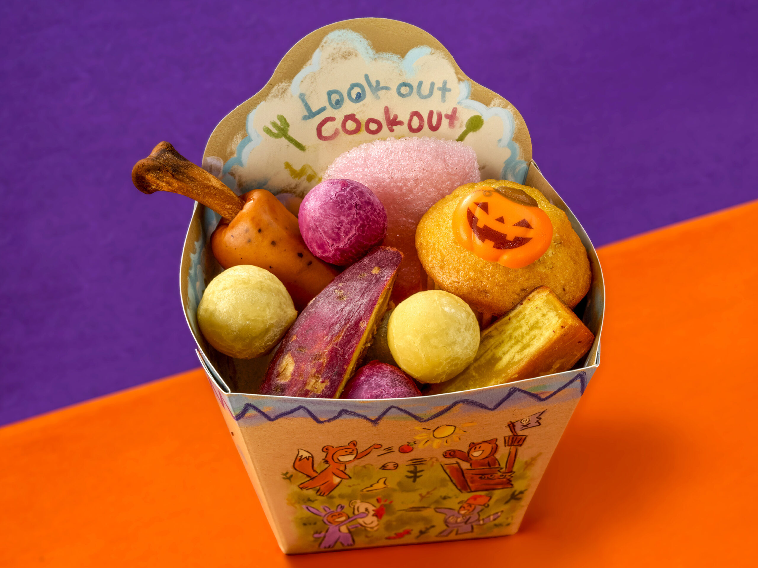 Look out Cook outのタグ付きテイクアウトボックスに入ったさつまいもボールやジャック・オ・ランタン型のパン菓子・骨付きソーセージ