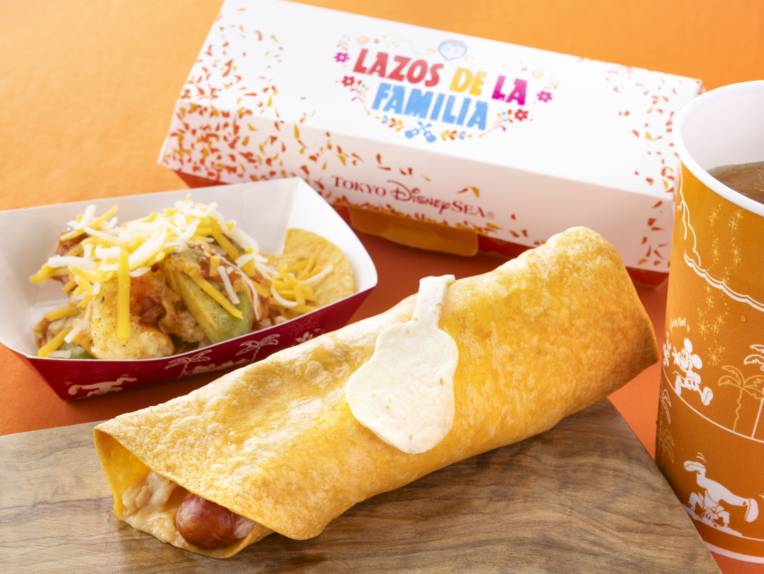 LAZOS DE LA FAMILIAのボックスとトルティーヤチーズドッグ・シュリンプのナチョス風・オレンジ色のドリンクカップ