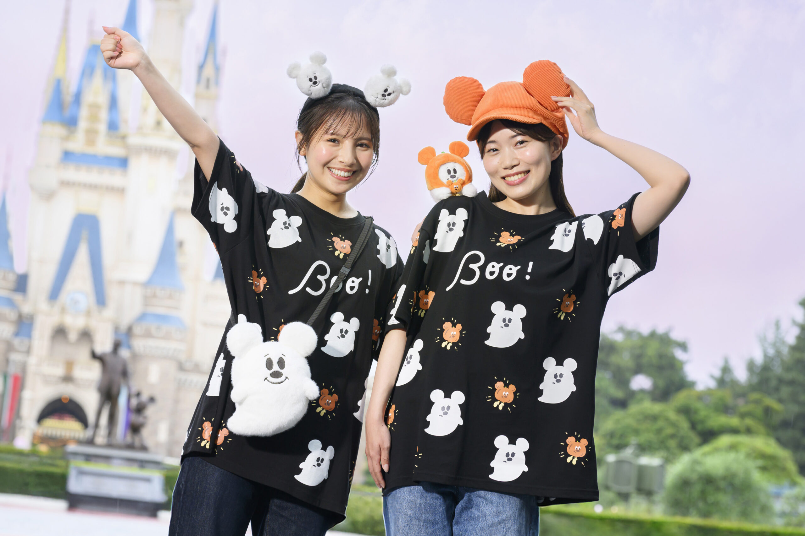 シンデレラ城を背景にBoo!柄のミッキーおばけTシャツとゴーストのぬいぐるみバッグ・キャップを身につけた2人