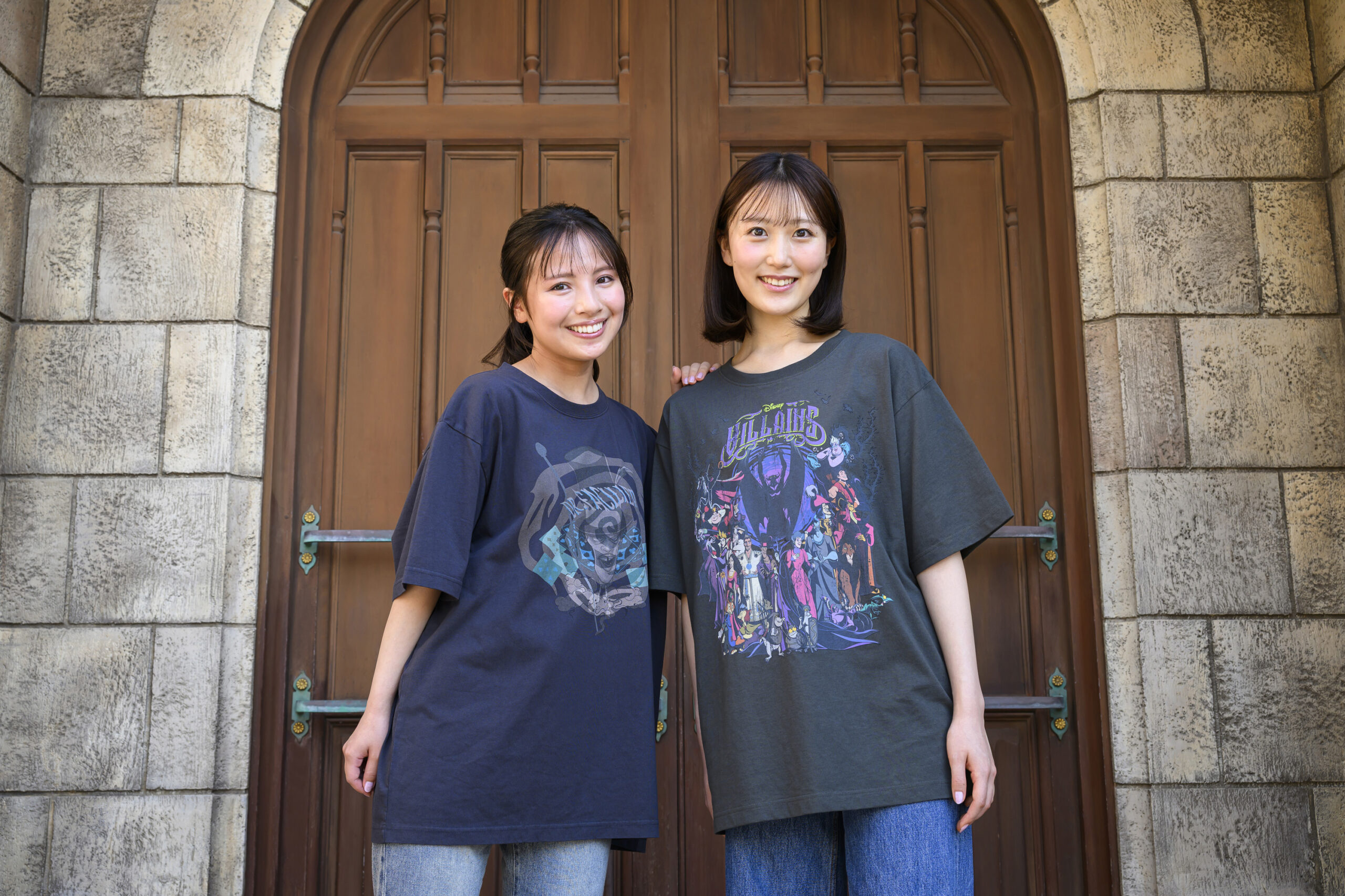 石壁とアーチ扉の前でディズニーヴィランズデザインのTシャツを着た2人の女性